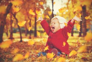 Child sitting and throwing leaves